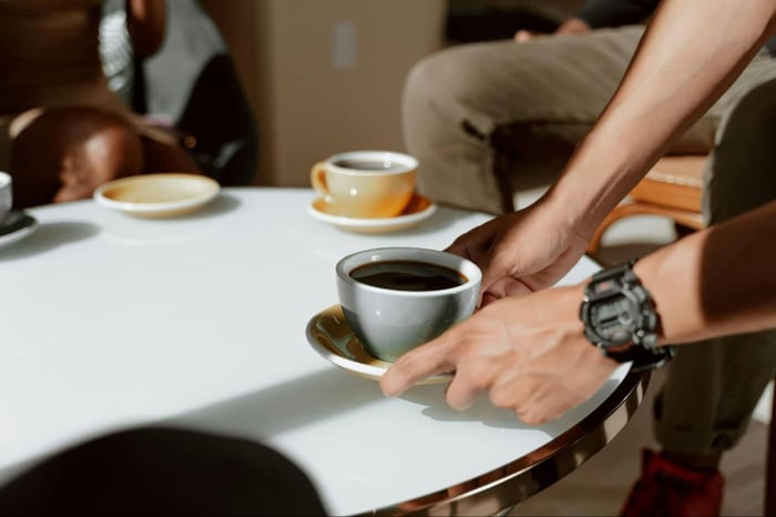 Man serving coffee on a white table.
