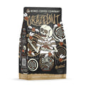 The front of a 12 ounce bag of Bones Coffee Company Crazelnut flavored coffee. It is hazelnut flavored, and it has a skeleton with crazy eyes and a cracked skull eating hazelnuts with other hazelnuts flying around on the art. 