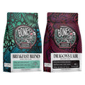 The front of two twelve ounce bags of Bones Coffee Company flavored coffee. The bag on the left is Breakfast Blend, and the bag on the right is Dragon’s Lair.