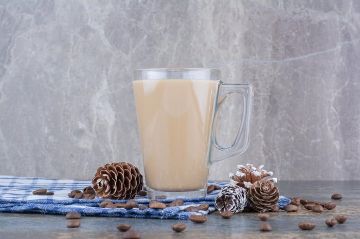 coffee milk glass with pinecones and coffee beans on tablecloth.