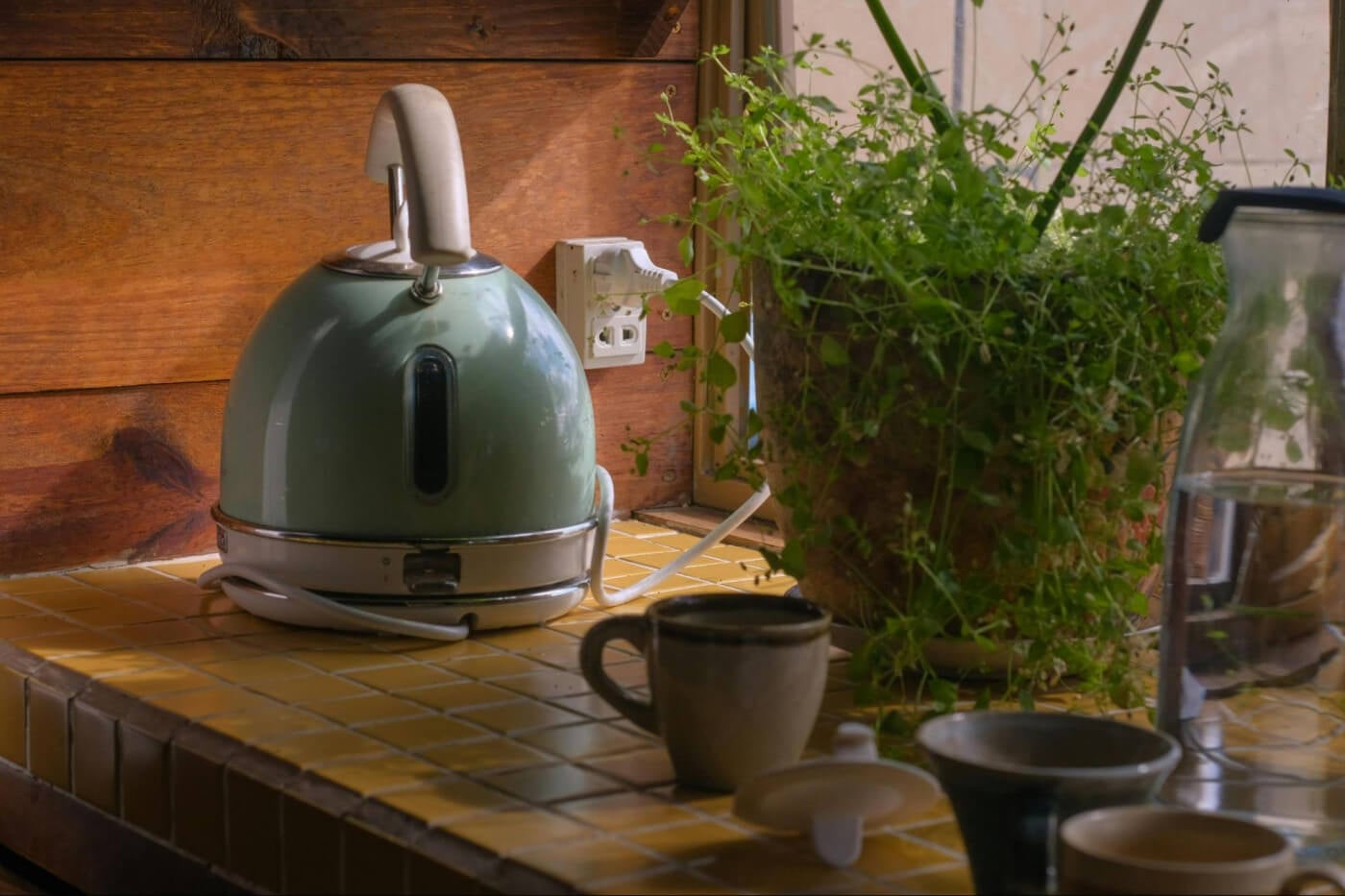 Vintage green kettle on yellow tile counter.