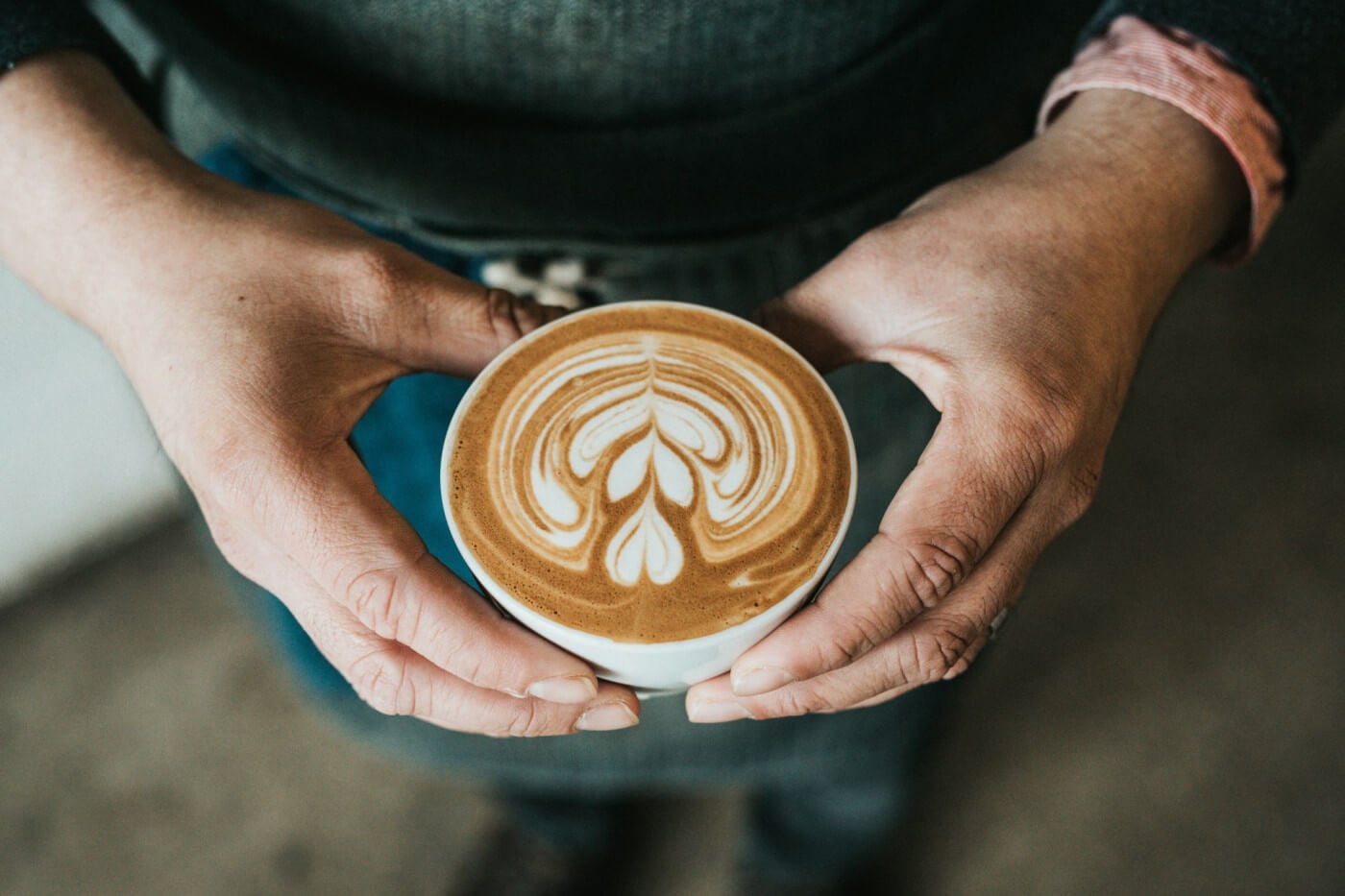 hands holding a cup of coffee with latte art
