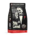 The front of a 12 ounce bag of Bones Coffee Company Holy Cannoli coffee. Its flavor is cannoli, and it has a skeleton wearing a suit with a red rose on the lapel holding a cannoli like a cigar on the art.
