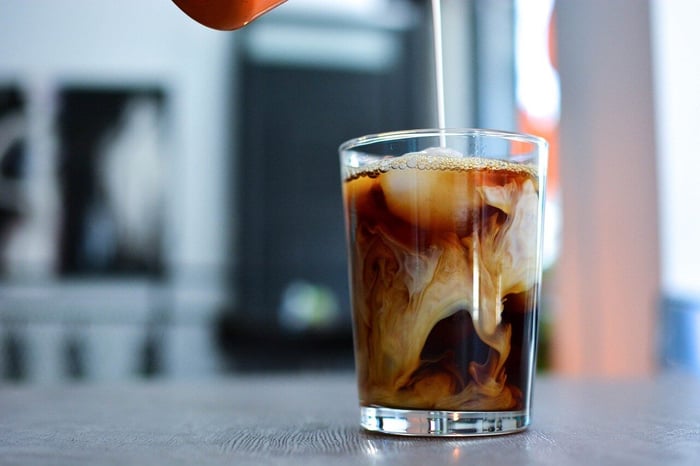 Cream swirling into iced coffee glass.