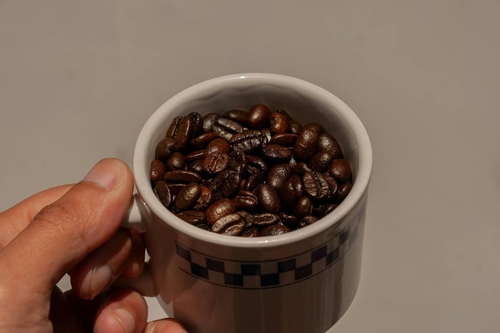 Hand Holding Cup with Coffee Beans