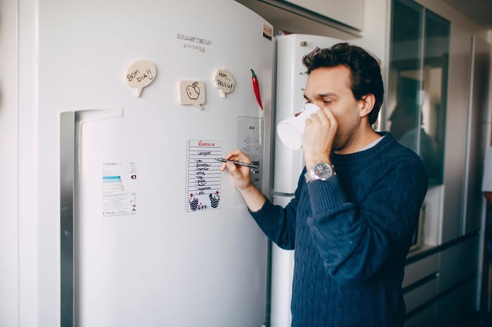 man drinking brewed coffee in front of fridge.