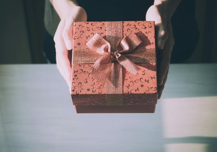 Hands holding brown gift box.
