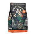 The front of a 12 ounce bag of Bones Coffee Company Salty Siren decaf coffee. Its flavor is sea salted caramel mocha, and it has a skeleton dressed up as a sailor holding a mermaid on the art.