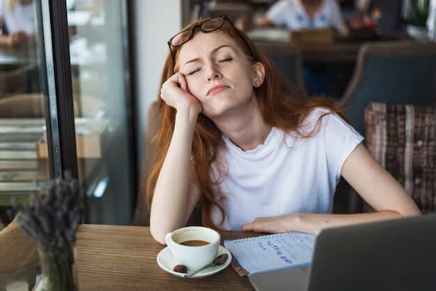sleeping woman with cofee cup and notes on desk