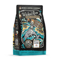 The front of a 12 ounce bag of Wicked Rum Barrel Aged Coffee. It has a skeleton in a pirate hat on a beach drinking coffee from a cup on a barrel of rum. It also has the logo of Wicked Dolphin on it.