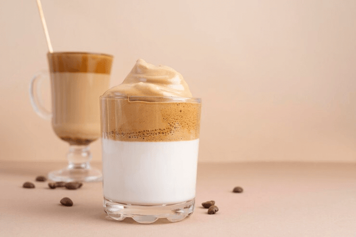 glass of Dalgona whipped coffee with a frothy top layer on milk